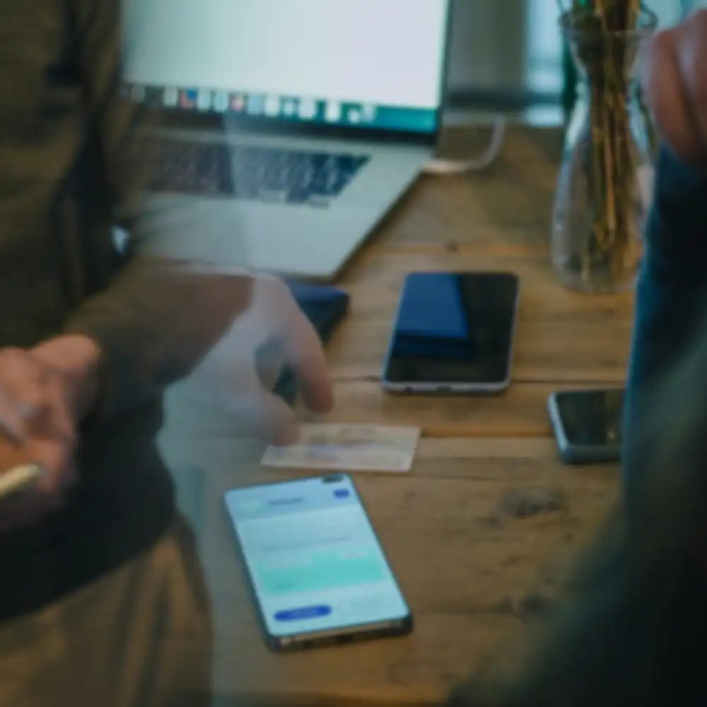 Ein angeschaltetes Smartphone liegt auf einem Schreibtisch mit weiteren Gegenständen