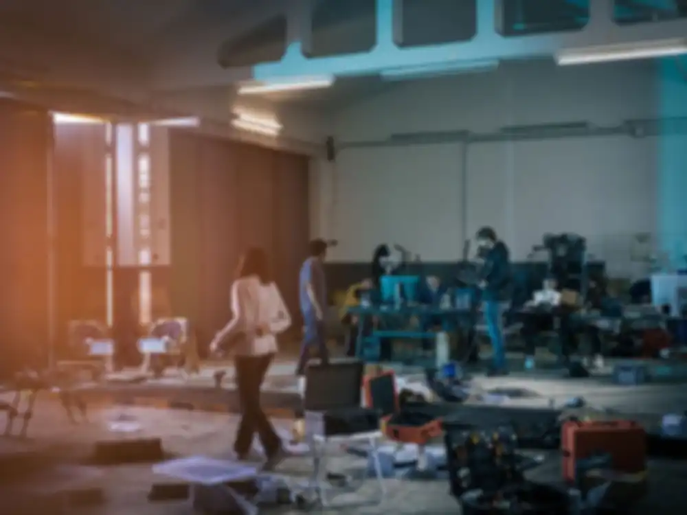 Mehrere Personen arbeiten in einer Halle. Überall sind Werkzeuge und Drohnenteile verteilt.