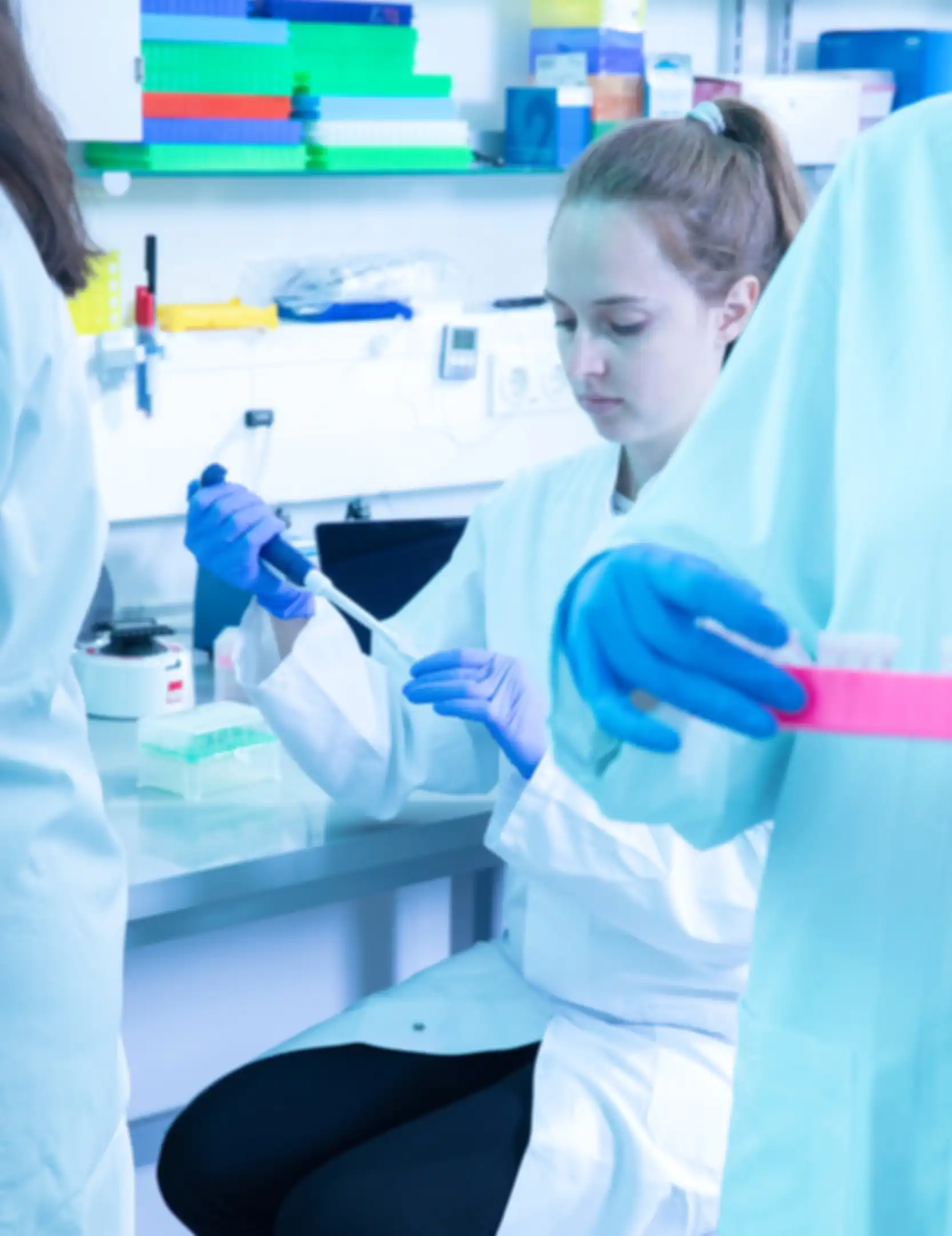 A woman in a lab coat is filling a small plastic capsule in a laboratory