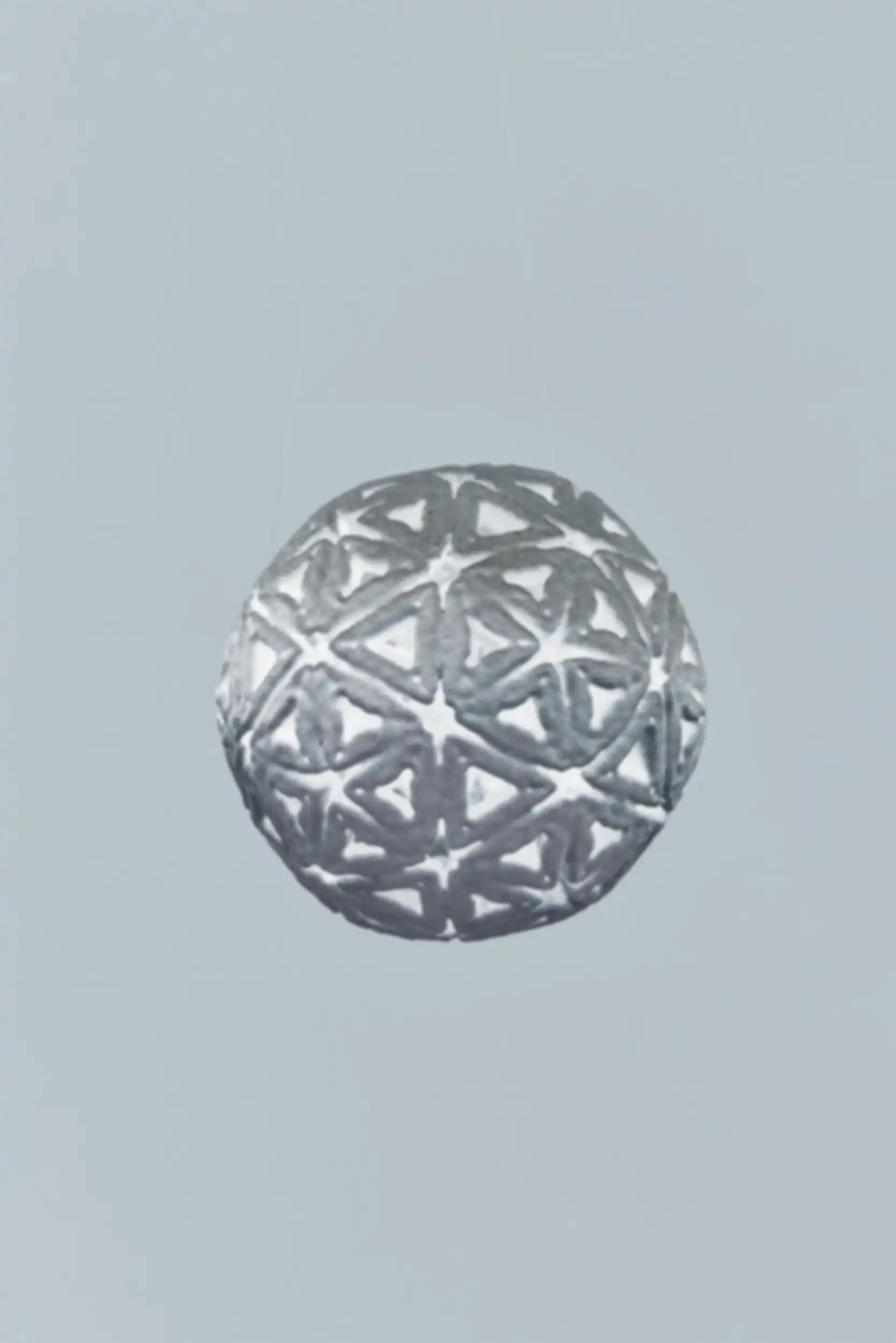 A gray, porous, geometric object with triangular openings