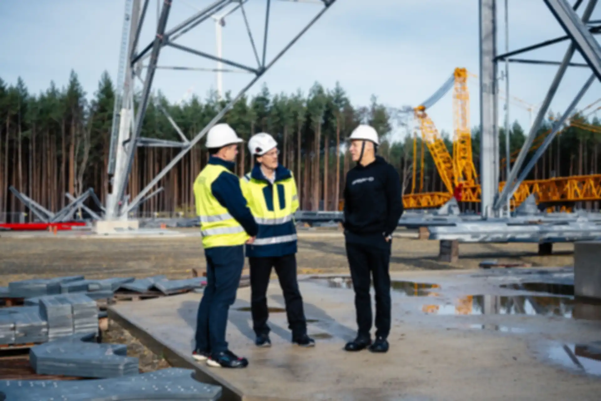 Three men talking on the construction site. The high-altitude wind turbine in the background