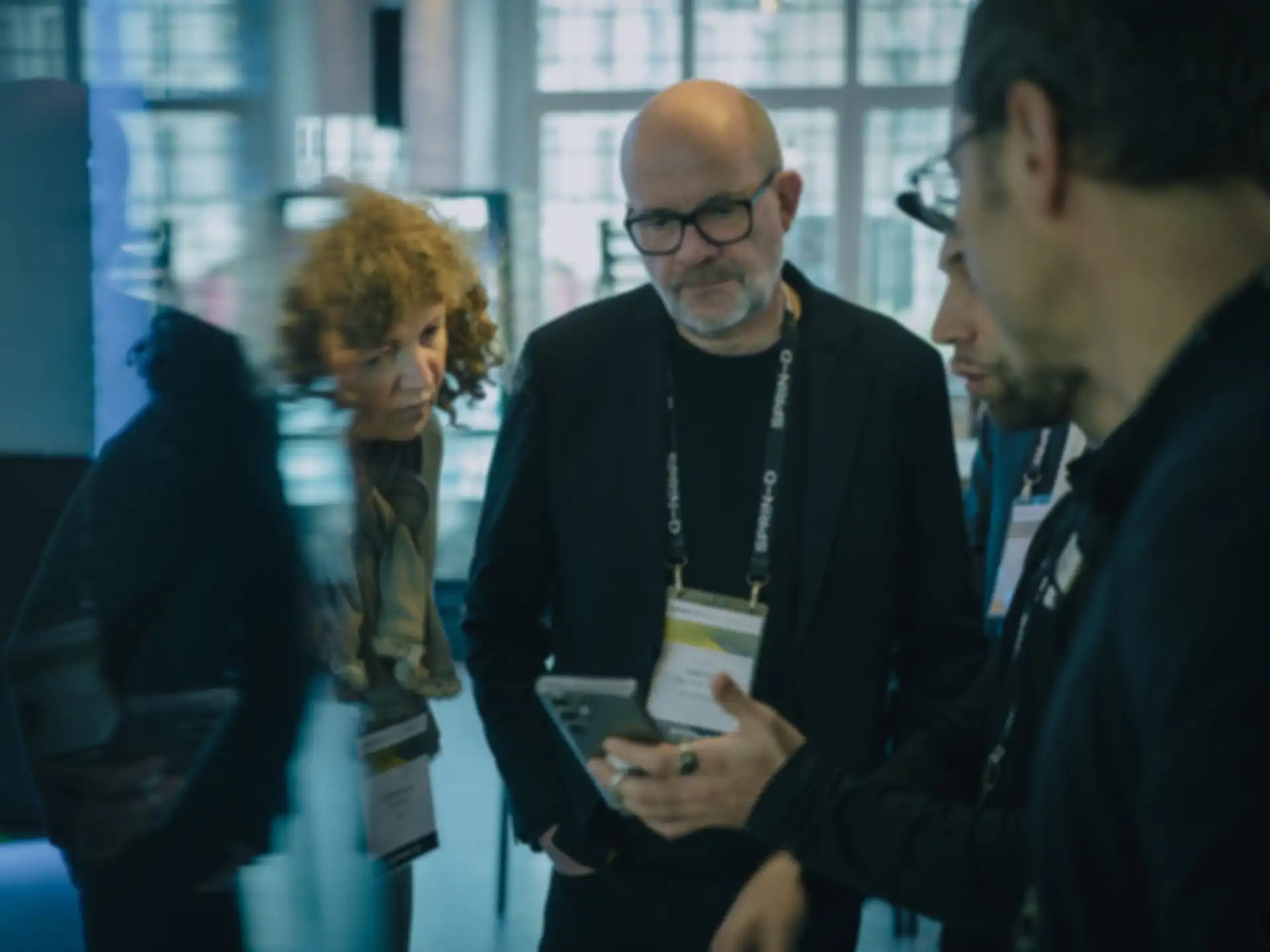 Rafael Laguna de la Vera bekommt auf einer Messe mit zwei weiteren Personen ein Produkt erklärt