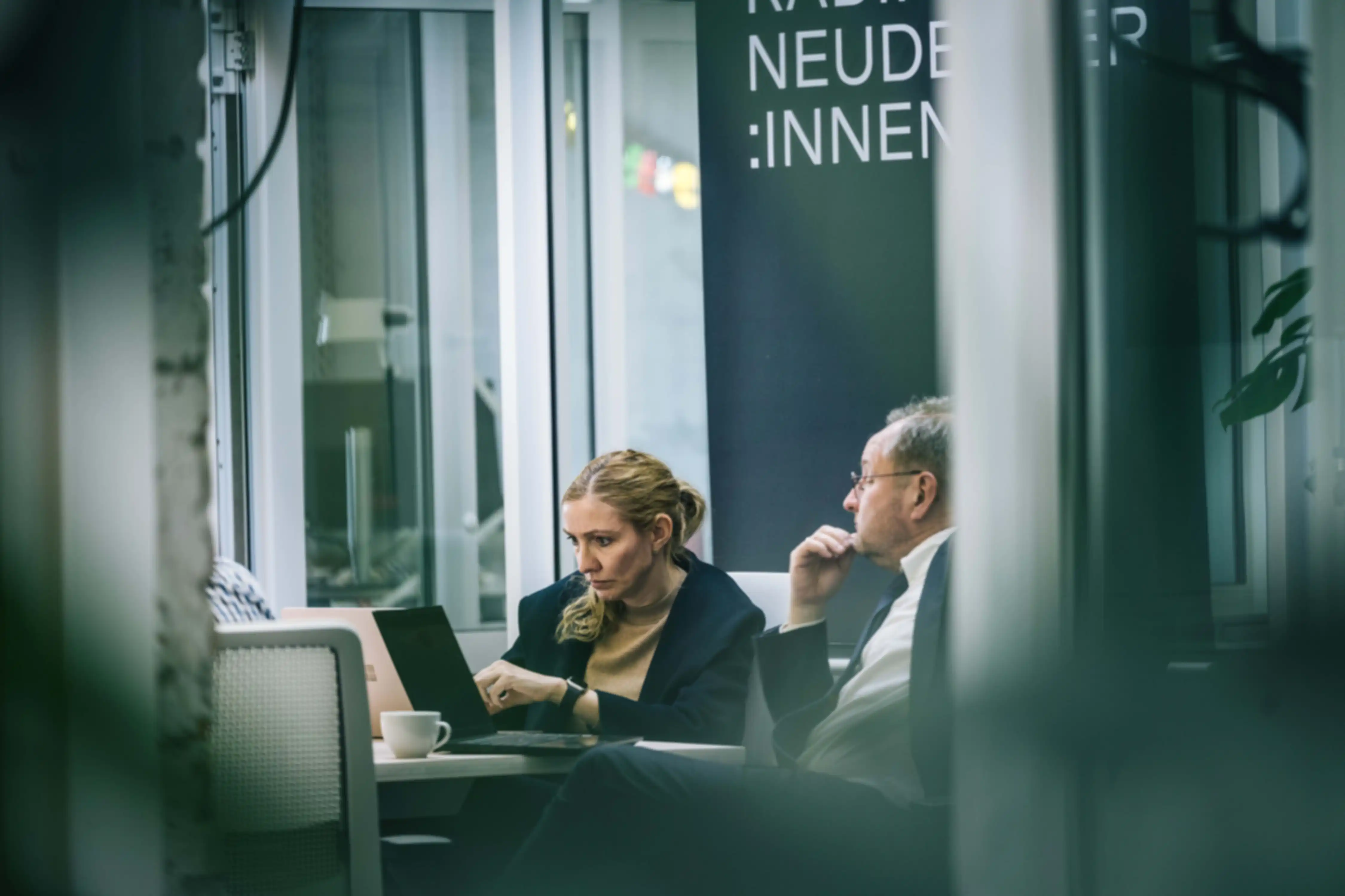 Two people are talking. They are looking at a laptop together.