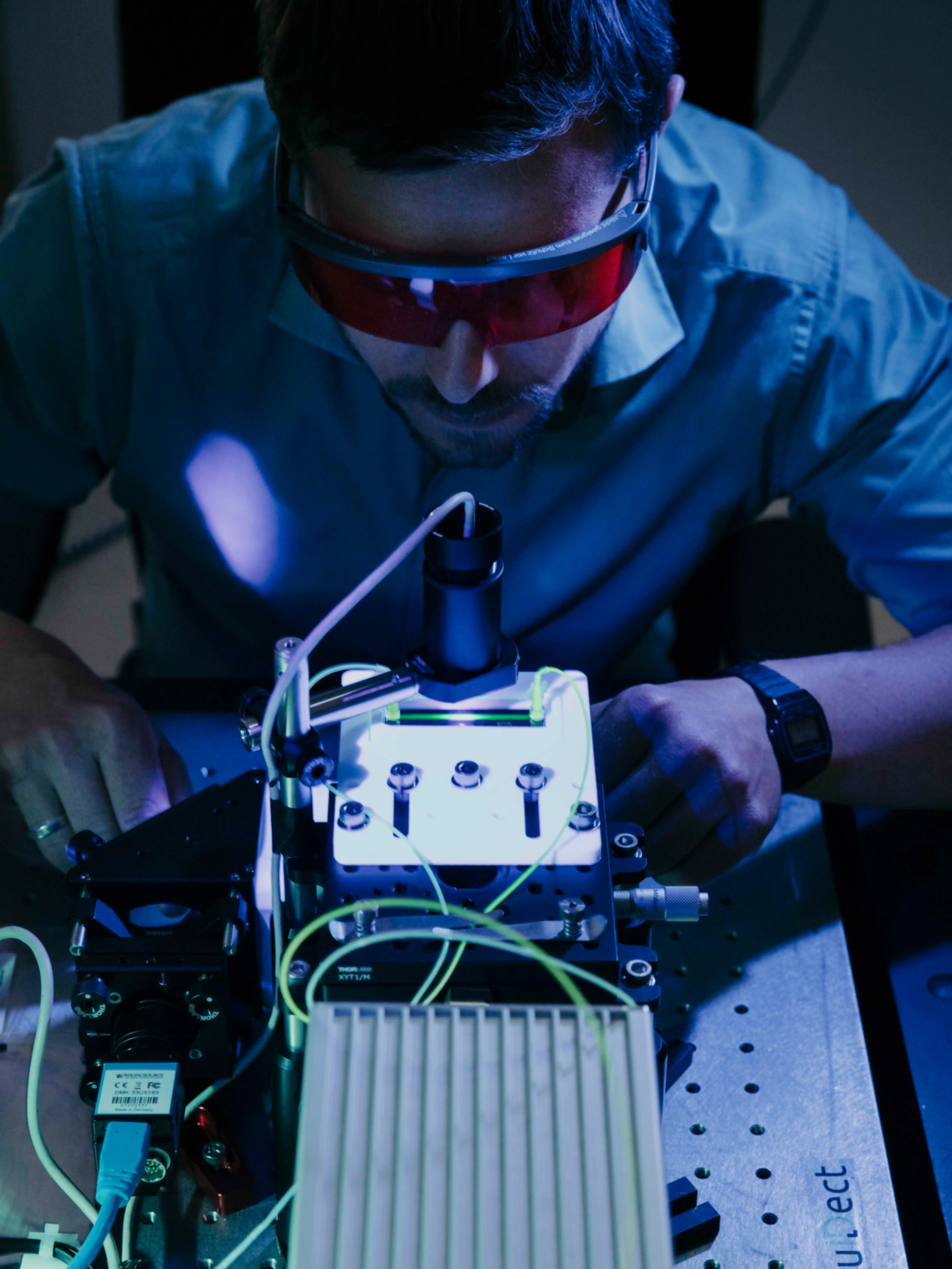 A man wearing red safety goggles is working on a piece of technical equipment