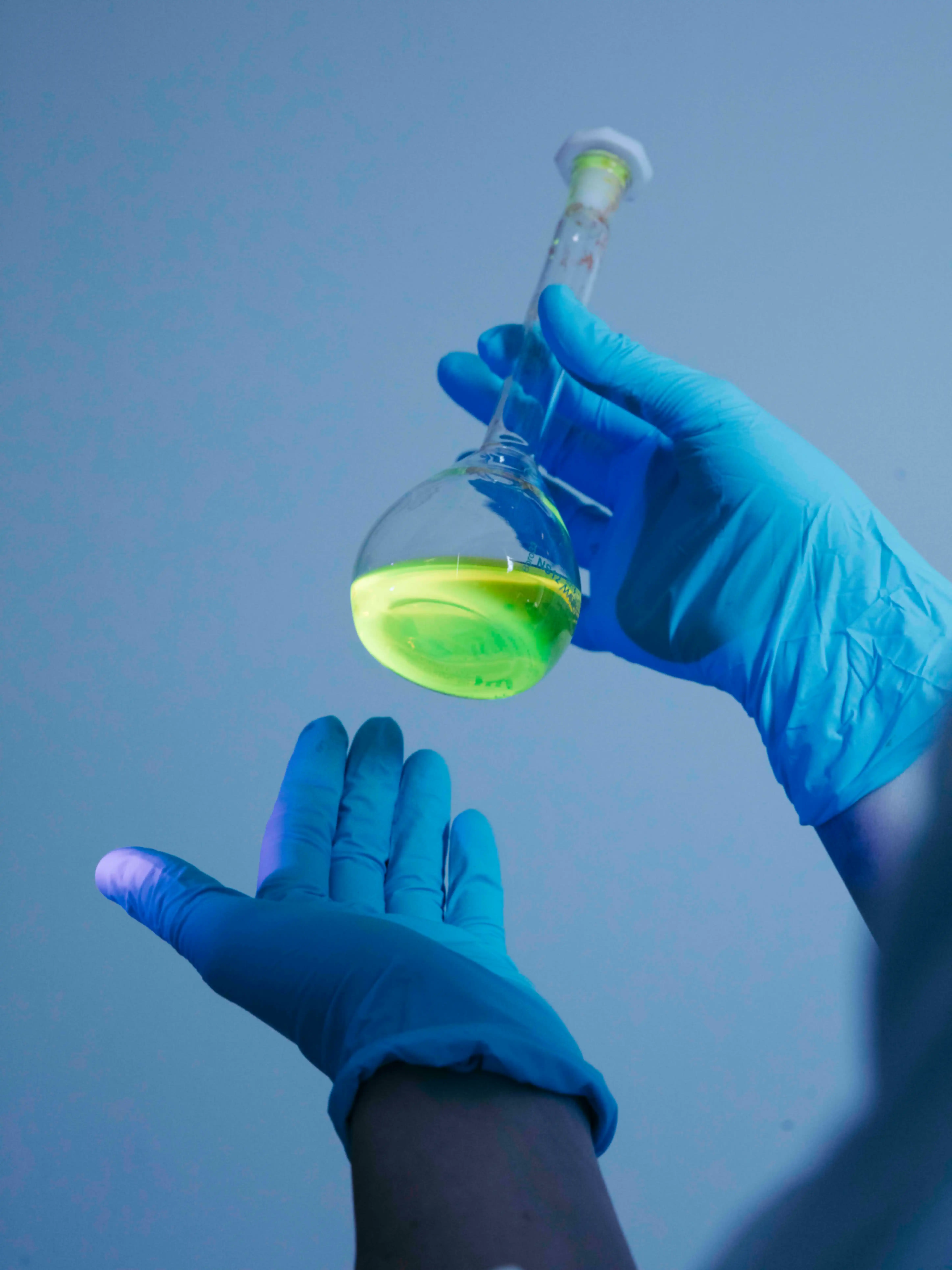 A person is holding a glass container filled with yellow liquid