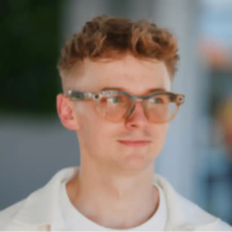 A portrait of Lukas Ziegler against a blurred background, looking to the side.