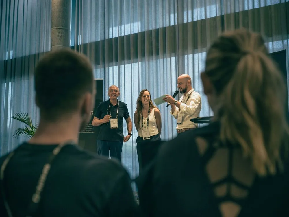 Drei Personen stehen auf der Bühne und sprechen über das Projekt