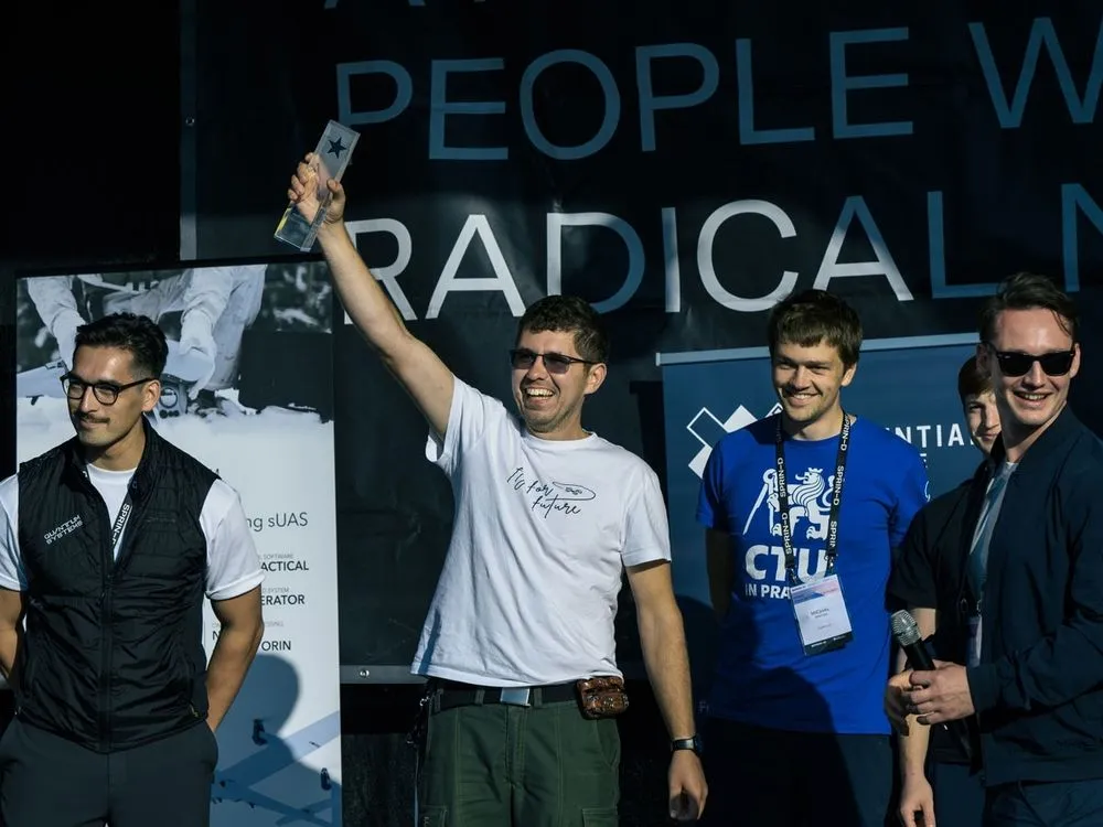 Das Gewinner Team steht auf der Bühne und hält einen Pokal in die Luft